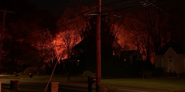 A fire can be seen burning behind a house in North Haven, Conn.