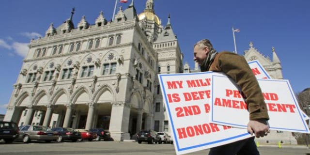 April 3, 2013: Jody Winslow, of Farmington, Conn., carries signs regarding the second amendment of the U.S. Constitution as he heads back to the Capitol in Hartford, Conn.