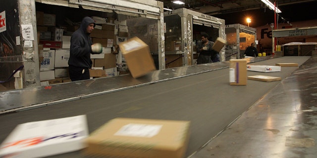 OAKLAND, CA - DECEMBER 18: FedEx workers place boxes on a conveyor belt at the FedEx sort facility at the Oakland International Airport December 18, 2006 in Oakland, California. Days before Christmas, FedEx will experience its busiest shipping day on the 19th of December and projects that it will deliver a record 9.8 million packages, well over a daily average of 6 million. (Photo by Justin Sullivan/Getty Images)