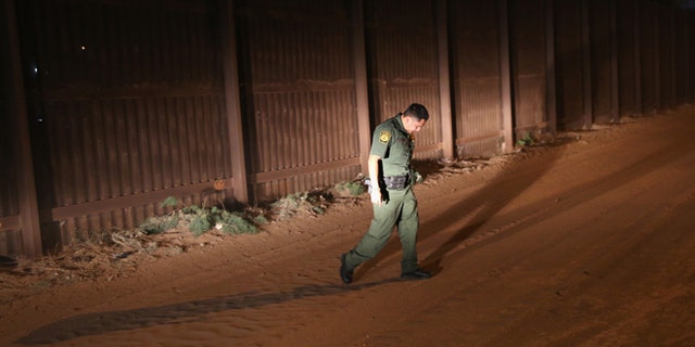 CALEXICO, CA - NOVEMBER 15: A U.S. Border Patrol agent looks for tracks along the U.S.-Mexico border fence on November 15, 2013 in Calexico, California. The fence separates the large Mexican city of Mexicali with Calexico, CA, and is a frequent illegal crossing point for immigrant smugglers. (Photo by John Moore/Getty Images)