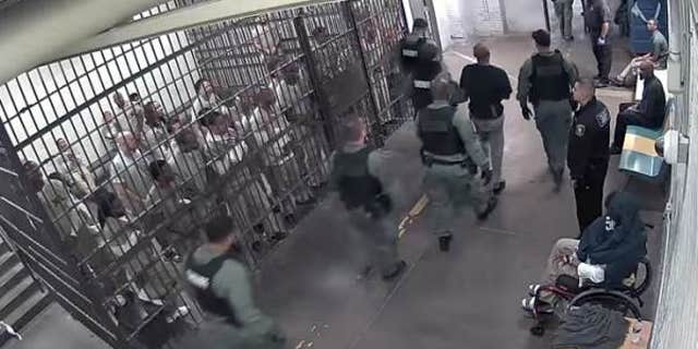 Law enforcement officers escort suspect Shomari Legghette past other detainees at the Cook County Jail.
