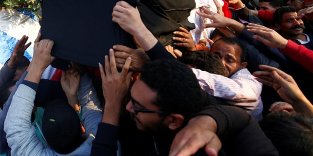 Relatives of a Christian woman who was killed in the bombing of Cairo's main Coptic cathedral, carry her body to bury at the Mokattam Cemetery in Cairo, Egypt.