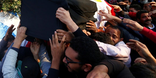 Relatives of a Christian woman who was killed in the bombing of Cairo's main Coptic cathedral, carry her body to bury at the Mokattam Cemetery in Cairo, Egypt.