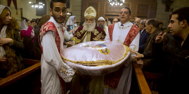 Coptic Orthodox priest, Tadros, center, carries communion bread during Christmas Eve Mass at Virgin Mary church in Cairo, Egypt, late Saturday, Jan. 6, 2018.