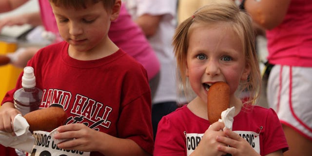 Children are shown enjoying a corn dog at the Tulsa State Fair in Oklahoma.