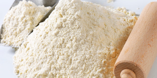 Pile of finely ground flour, wood rolling pin and metal scoop