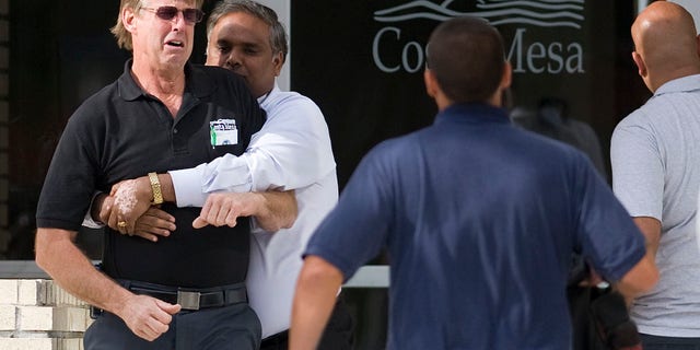 A city employee is held back by friends from confronting city managers at Costa Mesa City Hall after a maintenance worker jumped to his death Thursday, March 17, 2011 in Costa Mesa, Calif. (AP)