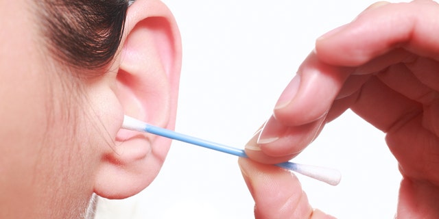 Photography closeup of a woman cleaning the ears with a cotton stalk;