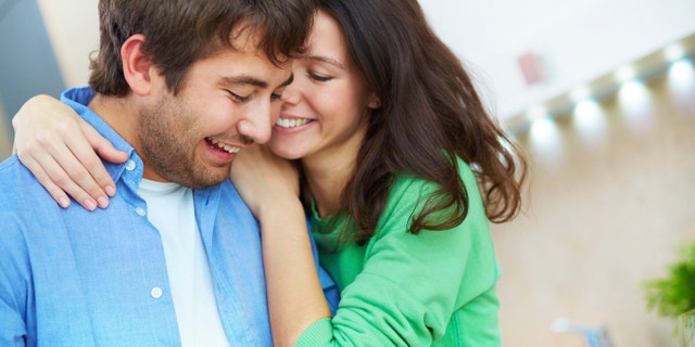Portrait of young woman embracing her husband in the kitchen