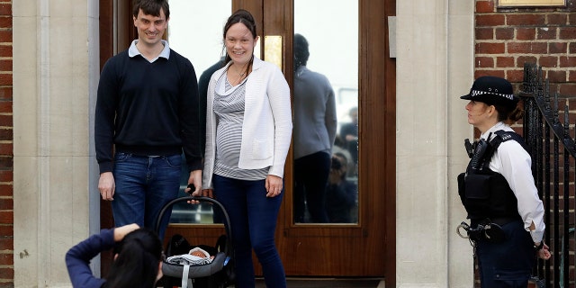 A couple pose for a photo with their newborn baby as they leave the Lindo wing at St Mary's Hospital in London London, Monday, April 23, 2018. Kensington Palace says Prince William's wife, the Duchess of Cambridge has entered a London hospital to give birth to the couple's third child. (AP Photo/Kirsty Wigglesworth)