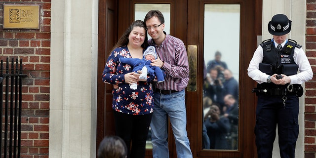 A couple pose for a photo with their newborn baby as they leave the Lindo wing at St Mary's Hospital in London London, Monday, April 23, 2018. Kensington Palace says the Duchess of Cambridge has given birth to her third child, a boy weighing 8 pounds, 7 ounces (3.8 kilograms). (AP Photo/Kirsty Wigglesworth)