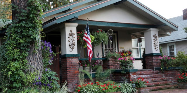 A Craftsman house displays the flag and flowers in front.