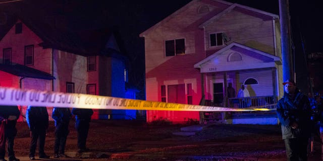 MINNEAPOLIS, MN - NOVEMBER 24: Police line up in front of a crime scene, and two people look on from their porch after 5 people were shot at a Black Lives Matters protest November 24, 2015 in Minneapolis, Minnesota. According to reports, a group of white men allegedly opened fire on the crowd after being escorted away from the encampment. (Photo by Stephen Maturen/Getty Images)