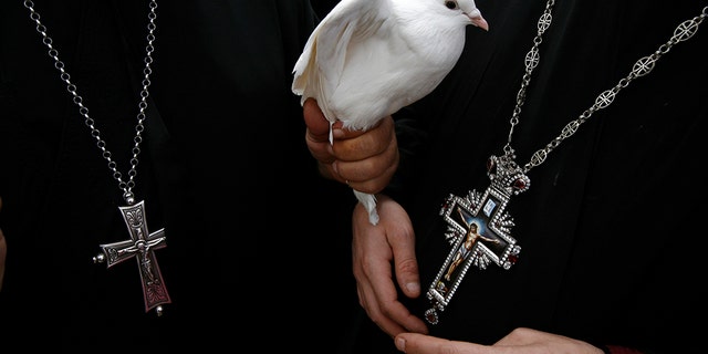 A Greek Orthodox priest holds a dove before a ceremony at the baptismal site known as Qasr el-Yahud on the banks of the Jordan River near the West Bank city of Jericho January 18, 2011
