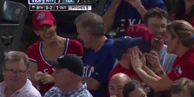 Shannon Moore, far left, and Sean Leonard celebrate catching a ball tossed into the stands during Wednesday's Rangers-Yankees game as 3-year-old Cameron Shores cries.