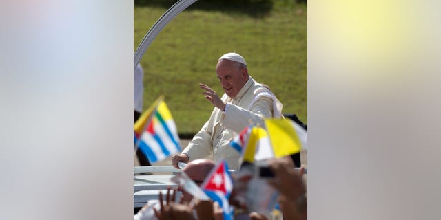 Pope Francis waves from his popemobile as he arrives for Mass at the Plaza of the Revolution in Holguin, Cuba, Monday, Sept. 21, 2015. Holguin's plaza was packed with thousands of people waving flags as Francis traveled in his popemobile through the crowd. Francis is the first pope to visit Holguin, Cuba's third-largest city. (AP Photo/Eduardo Verdugo)