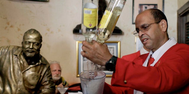 Bartender at El Floridita tavern in Havana under the bronze eye of former regular Ernest Hemingway.