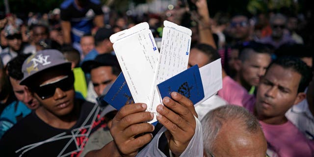 A man holds up airline tickets with destination to Ecuador, outside the Ecuadorian embassy, in Havana, Nov. 27, 2015.