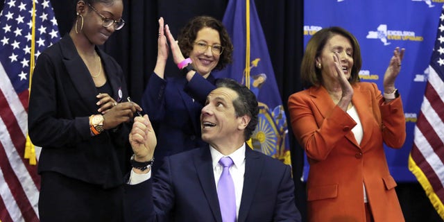 House Minority Leader Nancy Pelosi, D-Calif., right, applauds after New York Gov. Andrew Cuomo, seated, signed gun control legislation in New York City, May 1, 2018.
