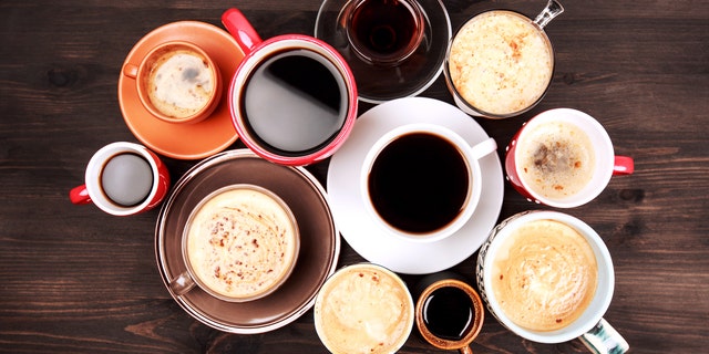 Many different cups of coffee on dark wooden table, top view.