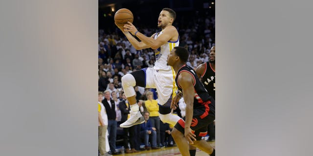 Golden State Warriors guard Stephen Curry, left, shoots against Toronto Raptors guard Kyle Lowry during the second half of an NBA basketball game in Oakland, Calif., Wednesday, Dec. 28, 2016. (AP Photo/Jeff Chiu)