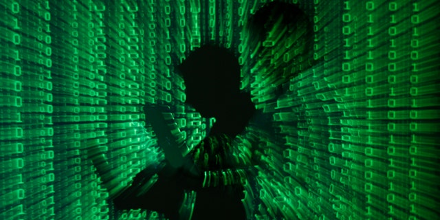 Photo illustration shows projection of binary code on a man holding a laptop computer. (Reuters)