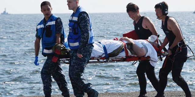 An injured USS Fitzgerald personnel is carried by U.S. military personnel, left, and Japanese Maritime Self-Defense Force members upon arriving to the U.S. Naval base in Yokosuka