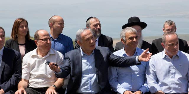 File - In this Sunday, April 17, 2016 file photo, Israeli Prime Minister Benjamin Netanyahu, center, poses with ministers prior to the weekly cabinet meeting in the Israeli controlled Golan Heights. Netanyahu has sparked a new diplomatic brushfire by declaring that the Golan Heights, seized from Syria in the 1967 war, is and should remain sovereign Israeli territory. But following some tough international criticism, Israeli officials have begun to backtrack, saying that a 1981 decision to apply Israeli law to the strategic plateau fell short of annexation and implying that Netanyahu misspoke. (AP Photo/Sebastian Scheiner, File)