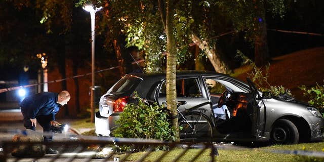 Police examine the scene of a shooting in southern Malmo, Sweden, Sunday Sept. 25, 2016. Swedish police say four people have been wounded in a shooting in Malmo, after gunmen on motor scooters opened fire Sunday evening on a car they had been chasing through a neighborhood. (Emil Langvad/TT via AP)