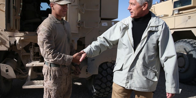 U.S. Secretary of Defense Chuck Hagel, right, shakes hands with U.S. Marine Lance CPL. Arron Corona as he works on a MRAP vehicle, at Camp Bastion, Afghanistan, Sunday, Dec. 8, 2013. Hagel spoke with troops and thanked them for being deployed for the holidays. (AP Photo/Mark Wilson, Pool)