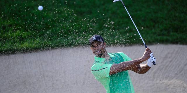 Tiger Woods hits out of a sand trap on the 10th hole during the first round of the Quicken Loans National golf tournament, Thursday, June 26, 2014, in Bethesda, Md. (AP Photo/Nick Wass)