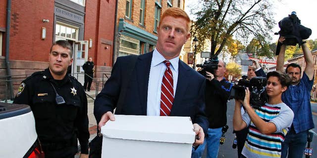 Former Penn State University assistant football coach Mike McQueary, center, leaves the Centre County Courthouse Annex in Bellefonte, Pa., Monday, Oct. 17, 2016. The trial for McQueary's defamation and whistleblower lawsuit against Penn State over how it treated him for complaining about assistant football coach Jerry Sandusky sexually abusing a boy got underway with opening arguments on Monday. (AP Photo/Gene J. Puskar)