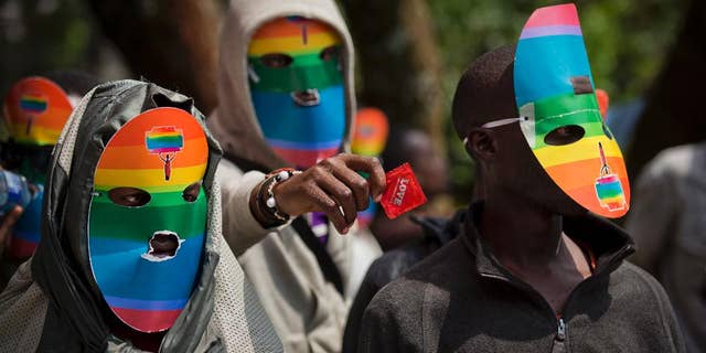 FILE - In this Monday, Feb. 10, 2014 file photo, Kenyan gays and lesbians and others supporting their cause wear masks to preserve their anonymity and one holds out a wrapped condom, as they stage a rare protest, against Uganda's increasingly tough stance against homosexuality and in solidarity with their counterparts there, outside the Uganda High Commission in Nairobi, Kenya. A Kenyan judge on Thursday, June 16, 2016 has upheld the use of enforced anal examinations to determine a suspect's sexual orientation, saying he found no violation of rights or the law and dismissed the petition by two men who were subjected to the procedures. (AP Photo/Ben Curtis, File)