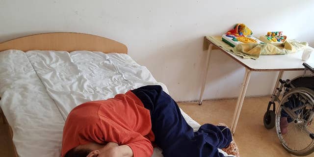The April 18, 2017 photo provided by the Mental Disability Advocacy Center MDAC on Wednesday, May 3, 2017 shows a patient lies on his bed at an institution in the city of God, near Budapest, where some 220 people reside. Hungarian authorities say they have suspended the director of a home for people with disabilities after a report from a civic group made serious claims of abuse and neglect.  (MDAC via AP)