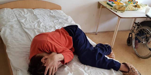 The April 18, 2017 photo provided by the Mental Disability Advocacy Center MDAC on Wednesday, May 3, 2017 shows a patient lies on his bed at an institution in the city of God, near Budapest, where some 220 people reside. Hungarian authorities say they have suspended the director of a home for people with disabilities after a report from a civic group made serious claims of abuse and neglect. (MDAC via AP)