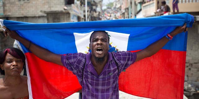 A supporter of presidential candidate Maryse Narcisse marches with a Haitian national flag during a demonstration in support of interim President Jocelerme Privert in Port-au-Prince, Haiti, Tuesday, June 14, 2016. Haiti's legislators will decide whether to pave way for a new interim leader until elections can be resolved or extend the term for Privert, whose 120-day mandate is due to expire today. ( AP Photo/Dieu Nalio Chery)