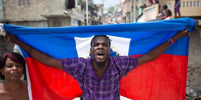 A supporter of presidential candidate Maryse Narcisse marches with a Haitian national flag during a demonstration in support of interim President Jocelerme Privert in Port-au-Prince, Haiti, Tuesday, June 14, 2016. Haiti's legislators will decide whether to pave way for a new interim leader until elections can be resolved or extend the term for Privert, whose 120-day mandate is due to expire today. ( AP Photo/Dieu Nalio Chery)