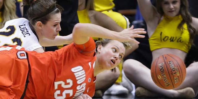 FILE - In this March 8, 2014 file photo, Ohio State guard Amy Scullion (25) and Iowa guard Samantha Logic go for a loose ball in the first half of an NCAA college basketball game in the semifinals of the Big Ten women's tournament in Indianapolis. Scullion had already graduated and been accepted into Ohio State’s medical school. A starter a year ago, she’s returning to a team that is short-handed because one player was kicked off the team and three others sustained season-ending knee injuries in the preseason. (AP Photo/Michael Conroy, File)