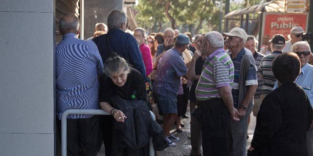 Elderly people, who usually get their pensions at the end of the month, wait outside a closed bank in Athens, Monday, June 29, 2015. Greece's five-year financial crisis took its most dramatic turn yet, with the cabinet deciding that Greek banks would remain shut for six business days and restrictions would be imposed on cash withdrawals. (AP Photo/Petros Giannakouris)
