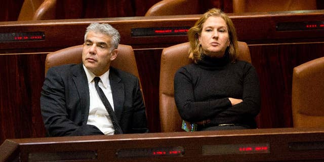 Israeli Finance Minister Yair Lapid, left, and Justice Minister Tzipi Livni sit following a vote at the Knesset, Israel's parliament in Jerusalem, Wednesday, Dec. 3, 2014. Israeli lawmakers voted Wednesday to dissolve the Knesset, a preliminary step that will pave the way for early elections two years ahead of schedule. (AP Photo/Sebastian Scheiner)
