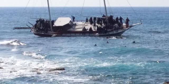 Migrants swim to reach the shore as others remainare on a listing vessel that later sunk in the eastern Aegean island of Rhodes, Greece on Monday, April 20, 2015. Greek authorities said that at least three people have died, including a child, after a wooden boat carrying tens of migrants ran aground off the island of Rhodes. (AP Photo/Michalis Loizos) GREECE OUT