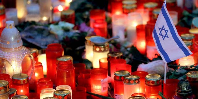 A small flag of Israel is pictured between candles and flowers after the reopening of the Christmas market at the Kaiser Wilhelm Memorial Church in Berlin, Germany, Thursday, Dec. 22, 2016 three days after a truck ran into the crowded market and killed several people. (AP Photo/Michael Sohn)