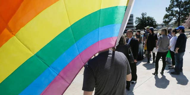 In this photo taken March 30, 2015, gay rights advocates gather at the Arkansas state Capitol in Little Rock, Ark. Arkansas Gov. Asa Hutchinson said Thursday, April 9, 2015, he doesn't see an urgent need for an executive order extending anti-discrimination workplace protections to gay and lesbian state employees after lawmakers approved a reworked religious objections bill. (AP Photo/Danny Johnston)