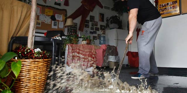 FILE - In this Jan. 5, 2016, file photo, Chris Lene sweeps water out of one of the businesses in the building he owns that was flooded by rainwater in Sacramento, Calif. Federal meteorologists proclaimed the end of the super-sized El Nino that further heated up the globe, but didn’t quite end California’s four year drought. The National Oceanic and Atmospheric Administration Thursday, June 9, 2016, said the El Nino has ended, 15 months after its birth in March 2015. El Nino is a natural warming of parts of the central Pacific that changes weather worldwide. (AP Photo/Rich Pedroncelli, File)