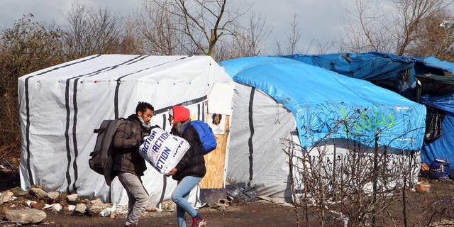 FILE - In this Thursday, March 3, 2016 file photo, unidentified migrants leave the makeshift camp near Calais, France. Residents of Champtercier fear their hamlet in the foothills of the Alps is about to become a new flashpoint for Europe’s migrant crisis: Its population of 800 is slated to grow sharply when it takes in 100 migrants from an overflowing camp in Calais next month. (AP Photo/Michel Spingler, File)