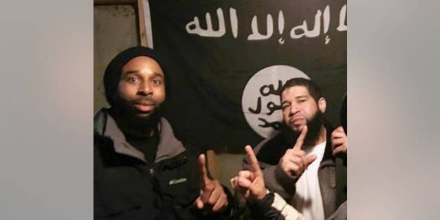FILE - In this undated file photo provided by the FBI shows Joseph D. Jones, left, and Edward Schimenti, both of suburban Chicago, pose in front of an Islamic State group flag. The two men, who are accused of seeking to provide material support to terrorists, pleaded not guilty Wednesday, May 3, 2017, at federal court in Chicago. Both were arrested by FBI agents on April 12, 2017. (FBI via AP, File)