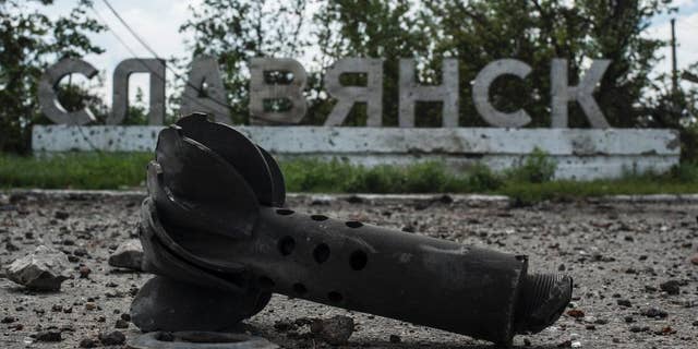 A part of the mortar shell is seen in front of a sign that reads 'Slovyansk', after heavy fighting between pro-Russian fighters and Ukrainian government troops just outside Slovyansk, eastern Ukraine, Wednesday, July 9, 2014. The rebels fled Slovyansk, a city of 100,000 that had been their stronghold, over the weekend as Ukrainian troops mounted an offensive. They left behind a city heavily damaged by fighting and riven by vehemently differing views. (AP Photo/Evgeniy Maloletka)