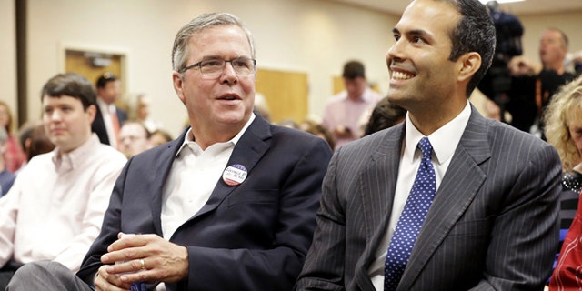 Former Florida Gov. Jeb Bush, left, sits with his son George P. Bush before speaking to supporters at Hardin-Simmons University, Tuesday, Oct. 14, 2014, in Abilene, Texas. Jeb Bush heads into West Texas to campaign for his son who is on the ballot this November as a candidate for state land commissioner. (AP Photo/LM Otero)