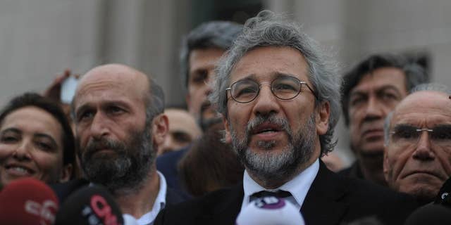 Can Dundar, the editor-in-chief of opposition newspaper Cumhuriyet, right, and Erdem Gul, left, the paper's Ankara representative, speak to the media after their trial in Istanbul, Friday, March 25, 2016. The trial of two Turkish journalists accused of revealing state secrets and helping a terrorism organization over their reports on alleged government-arms smuggling to Syrian rebels was adjourned on Friday after opposition lawmakers refused to leave the courthouse in defiance of a controversial ruling to proceed behind closed doors.(AP Photo/Omer Kuscu)