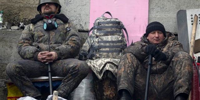 Anti-government protesters rest as they man a barricade in central Kiev, Ukraine, Friday, Feb. 21, 2014. European officials say Ukrainian protesters have agreed to a deal with Ukraine's president on defusing a deadly political crisis. Earlier Friday President Viktor Yanukovych announced early elections and promised to invite the opposition into the government. (AP Photo/Darko Bandic)